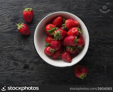 Strawberry in white plate on dark wooden background. Strawberry in white plate on dark wood