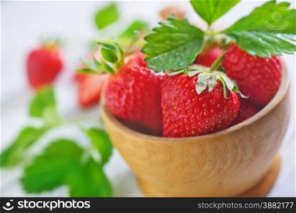 strawberry in wooden bowl and on a table