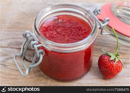 Strawberry jam in a jar on wood.. Strawberry jam in a jar on wood