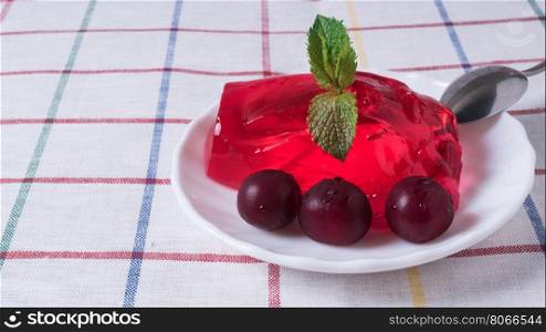 Strawberry jelly with cherries on the plate with ripe. Strawberry jelly on the plate with ripe cherries