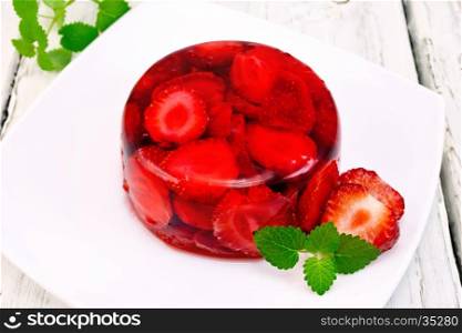 Strawberry jelly with mint and berries in a plate on a kitchen towel on the background of wooden boards