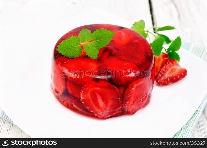 Strawberry jelly with mint and berries in a plate on a napkin on the background light wooden boards