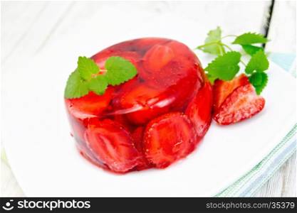 Strawberry jelly with mint and berries in a plate on a towel on the background light wooden boards