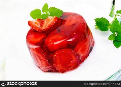 Strawberry jelly with mint and berries in a white plate on a towel on the background of wooden boards