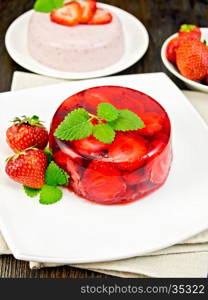 Strawberry jelly with mint and berries in the plate on the towel, panna cotta on a background of wooden boards