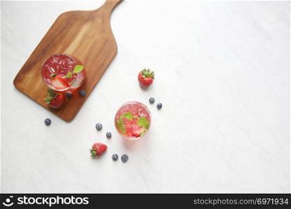 Strawberry juice cocktail with ice and mint on white tone amd wooden