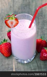 Strawberry milk shake with strawberries on wooden background, soft focus on strawbery on the glass