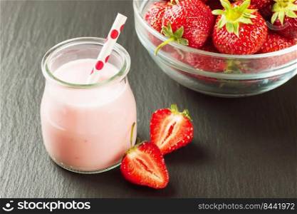 Strawberry milkshake in the glass jar with drinking straw on black slate background.. Strawberry milkshake in the glass jar on black slate background