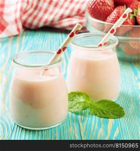 Strawberry milkshake in the glass jar with drinking straw on blue wooden table.. Strawberry milkshake in the glass jar