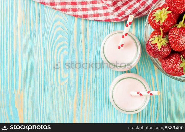 Strawberry milkshake in the glass jar with drinking straw on blue wooden table. Top view, flat lay, mockup with copy space for text. Strawberry milkshake in the glass jar on blue wooden background