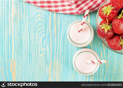 Strawberry milkshake in the glass jar with drinking straw on blue wooden table. Top view, flat lay, mockup with copy space for text. Strawberry milkshake in the glass jar on blue wooden background