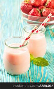 Strawberry milkshake in the glass jar with drinking straw on blue wooden table. Strawberry milkshake in the glass jar