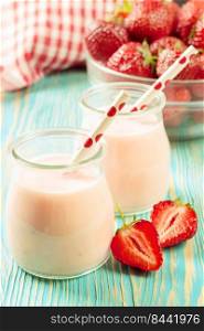 Strawberry milkshake in the glass jar with drinking straw on blue wooden table. Strawberry milkshake in the glass jar on white wooden background