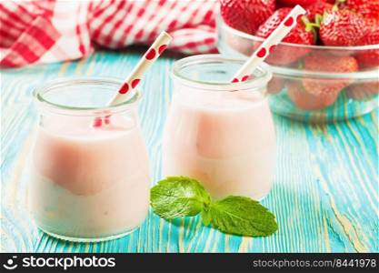 Strawberry milkshake in the glass jar with drinking straw on blue wooden table. Strawberry milkshake in the glass jar on blue wooden background