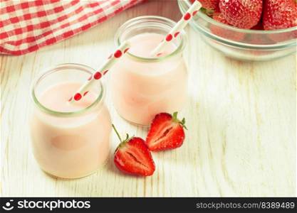 Strawberry milkshake in the glass jar with drinking straw on white wooden table. Mockup with copy space for text. Strawberry milkshake in the glass jar on white wooden background