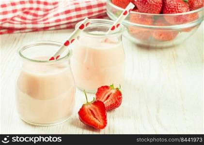 Strawberry milkshake in the glass jar with drinking straw on white wooden table. Mockup with copy space for text. Strawberry milkshake in the glass jar on white wooden background