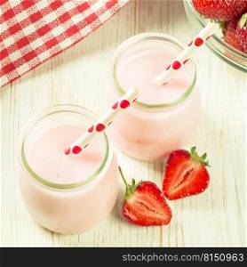 Strawberry milkshake in the glass jar with drinking straw on white wooden table. square photo. Strawberry milkshake in the glass jar on white wooden background