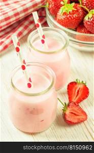 Strawberry milkshake in the glass jar with drinking straw on white wooden table. vertical photo. Strawberry milkshake in the glass jar on white wooden background