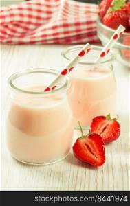 Strawberry milkshake in the glass jar with drinking straw on white wooden table. vertical photo. Strawberry milkshake in the glass jar on white wooden background