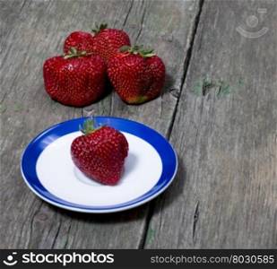 strawberry on a saucer and behind three strawberries, a berry subject, spring