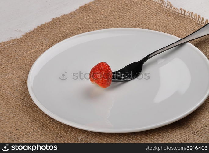 Strawberry on fork and plate