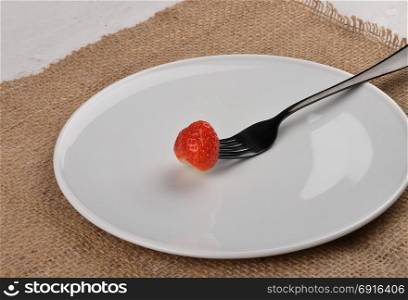 Strawberry on fork and plate