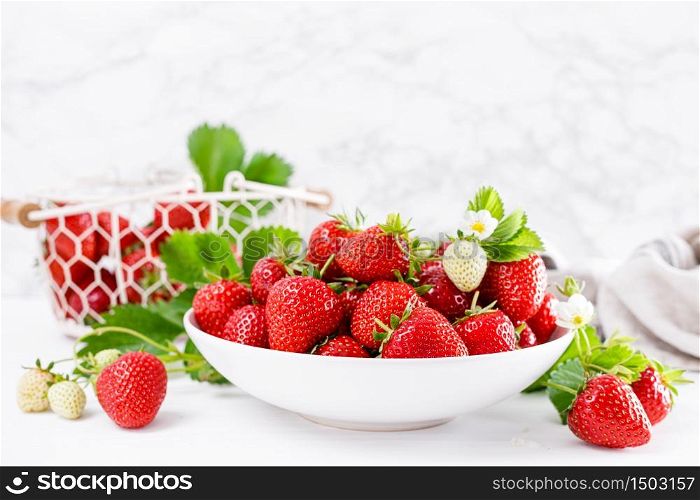 Strawberry on plate with twigs and leaves on white background