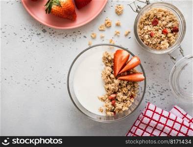 Strawberry organic granola with milk and fresh berries on light kitchen board. Top view.