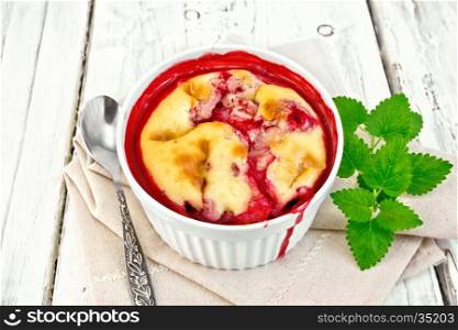 Strawberry pudding in a bowl with berries and mint on a napkin on a light wooden planks