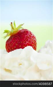 Strawberry sinking in to whipped cream over light green background