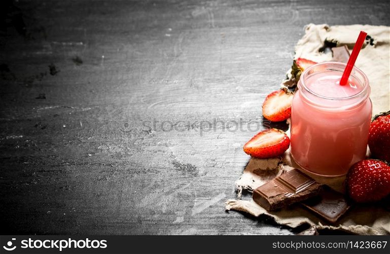 Strawberry smoothies with ripe berries. On a black wooden background. Strawberry smoothies with ripe berries.
