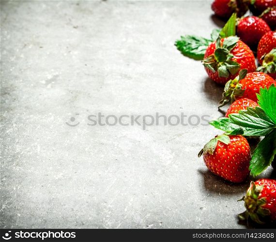 Strawberry with green leaves. On the stone table.. Strawberry with green leaves.