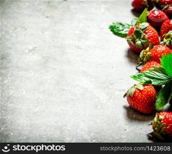 Strawberry with green leaves. On the stone table.. Strawberry with green leaves.