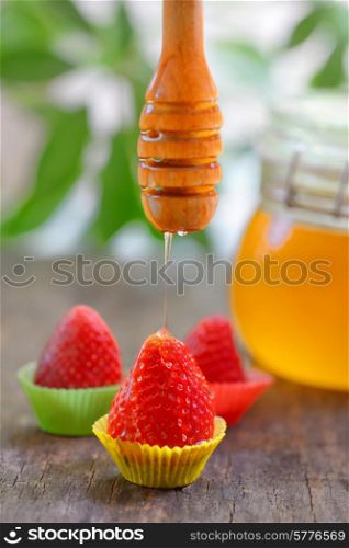 strawberry with honey dripping on old table