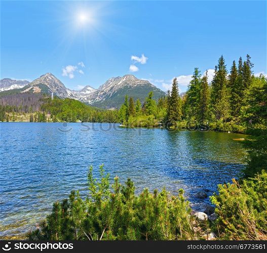 Strbske Pleso spring view with mountain lake (Slovakia) and sunshine in blue sky/