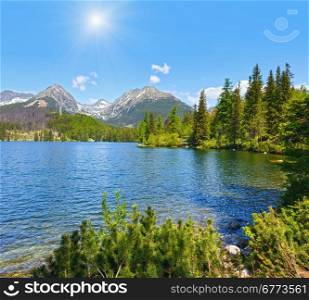 Strbske Pleso spring view with mountain lake (Slovakia) and sunshine in blue sky/