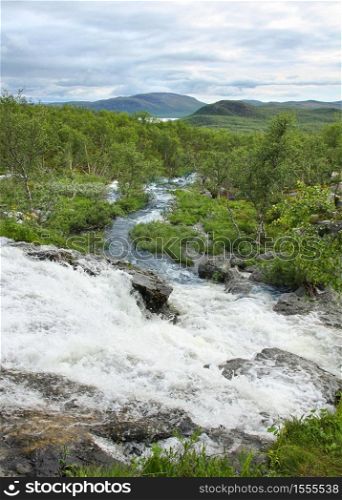 Streamlet waterfall from Lake Tsahkal in Northern Lapland wilderness, fells on the background