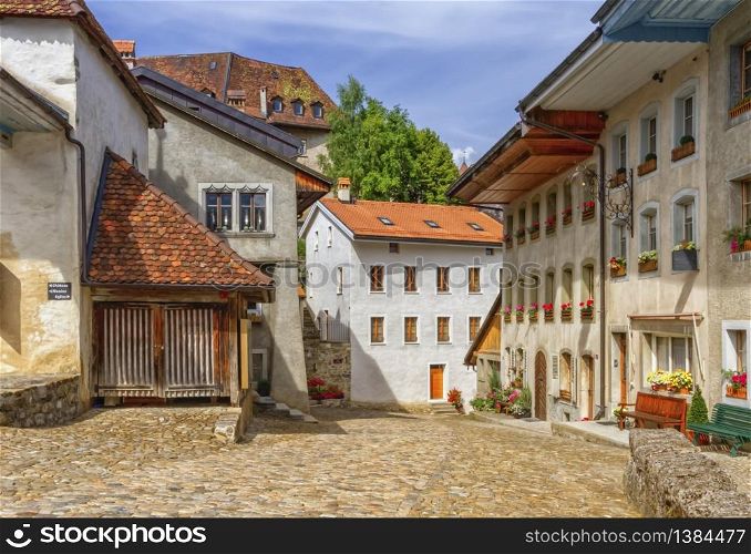Street and houses in Gruyere village in Fribourg canton by beautiful day, Switzerland. Gruyere village in Fribourg canton, Switzerland