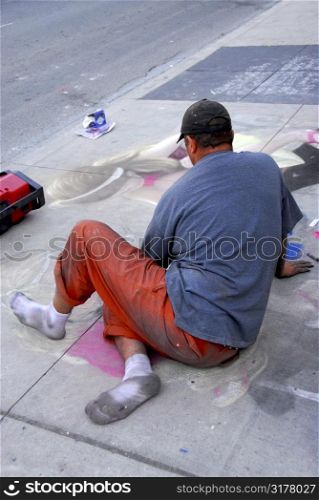 Street artist drawing with chalk on sidewalk