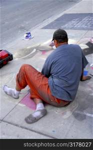 Street artist drawing with chalk on sidewalk