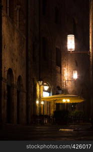 Street Cafe at the old town San Gimignano in evening time at the province of Siena. Tuscany, Italy