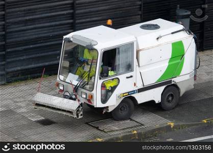 Street cleaning machine working in city. Sweeper cleaning the sidewalk with pressurized water. Maintenance or cleaning concept