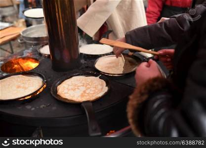 street cooking of pancakes on a large circular grill
