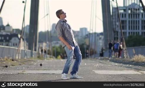 Street dancer dressed in casual clothes perfoming freestyle dance over industrial background