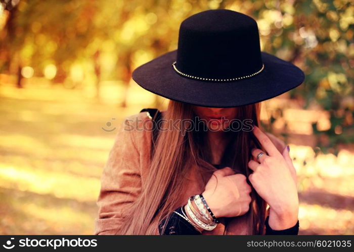 Street fashion concept - closeup portrait of a pretty girl. Wearing hat and suede jacket holding bag with fringe. Beautiful autumn woman.