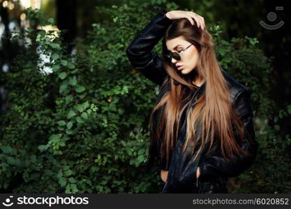 Street fashion concept - closeup portrait of a pretty girl. Wearing leather jacket, round sunglasses. Autumn woman. Artsy bohemian rock style. Fall fashion.