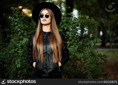 Street fashion concept - pretty young slim woman in rock black style, wearing stylish sunglasses and black leather jacket. Young cheerful fashion woman