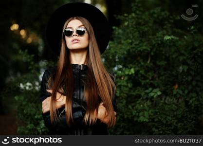 Street fashion concept - pretty young slim woman in rock black style, wearing stylish sunglasses and black leather jacket. Young cheerful fashion woman