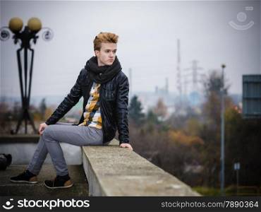 Street fashion. Young fashionable man guy with stylish hair posing outdoor on cityspace background
