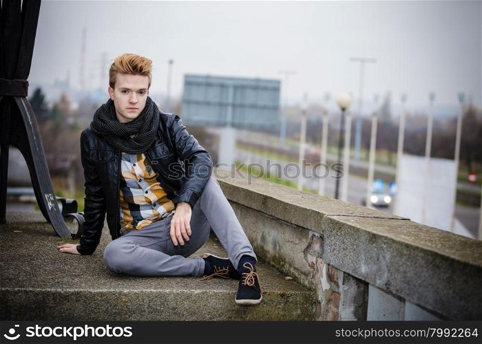 Street fashion. Young fashionable man guy with stylish hair posing outdoor on cityspace background